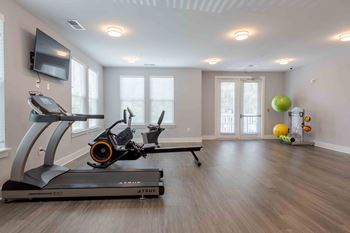 A treadmill and a stationary bike are in a room with a television.